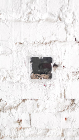 old electrical outlet on a white brick wall, closeup of photoの写真素材