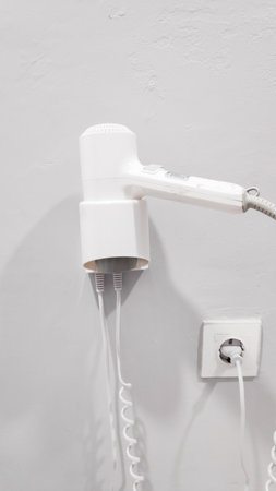 Close-up of a white hair dryer on a white wall.の写真素材