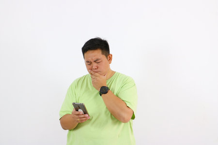 A young Asian man shows curiosity and suspicion on his face.の写真素材