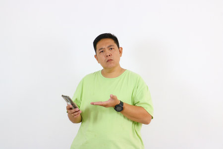 A young man's portrait shows curiosity and suspicion while on phone.の写真素材