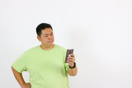 A young man's curious and suspicious expression while holding phone.の写真素材