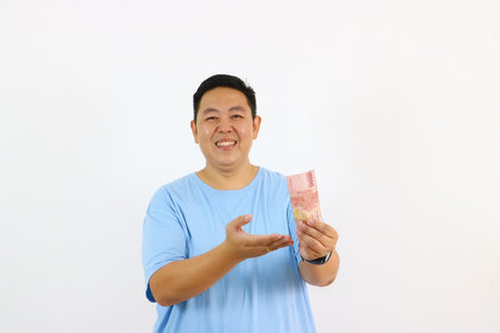 Young asian guy pointing finger up to money and smiling