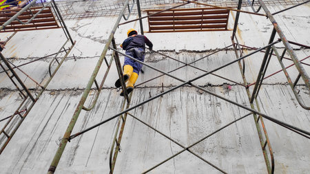 Detailed photo of working people wearing safety gear and yellow boots on a construction site with...