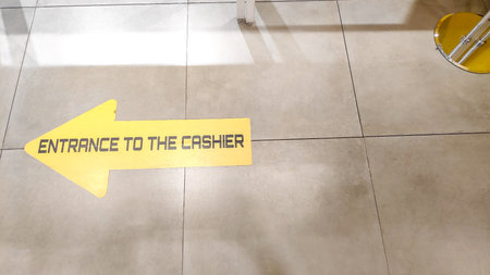 Detailed photo of a sign with text ENTRANCE TO THE CASHIER on beige tiled floor at mall