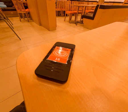 Detailed photo of a Yoshinoya customer queue pager with orange label waiting for order pickup. Bandung, 12 July 2025.のeditorial素材
