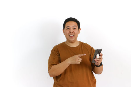 An Asian male individual reacting with a winning gesture and excited facial expression while using a...