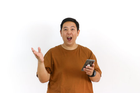 An Indonesian Asian man shouts into his hand while holding his smartphone on a white background.の写真素材