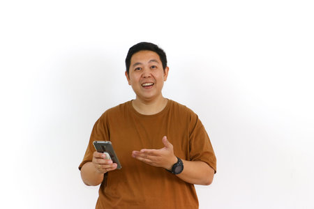An Asian male individual reacting with a winning gesture and excited facial expression while using a smartphone.の写真素材
