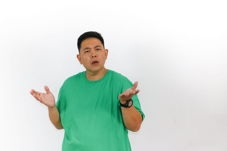 Portrait of an Asian man who is thinking, looking up, standing with his hands crossed, with finger on his chin.の写真素材