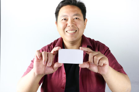 Smiling Handsome asian guy pointing finger at an advertisement, business card, ID card, or...
