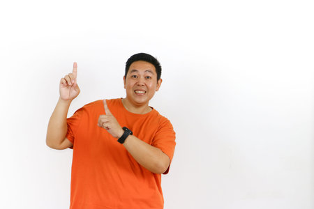 Handsome male model in his forties wearing a casual orange t-shirt, pointing excitedly to the large blank white space on the right, perfect for your text or logo.の写真素材