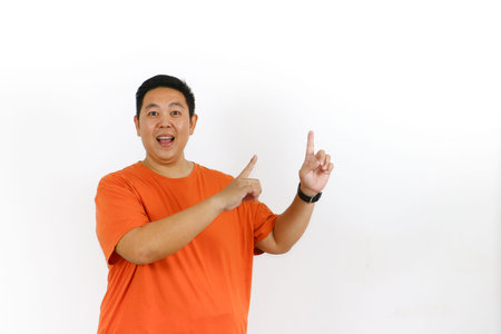 Happy man poses in a studio setting, gesturing towards the blank area, suggesting a big product launch, special promotion, announcement, or new opportunity to potential customers.の写真素材