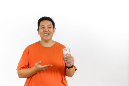Happy Asian male model holding money with clenched fist, cheering and expressing excitement about...