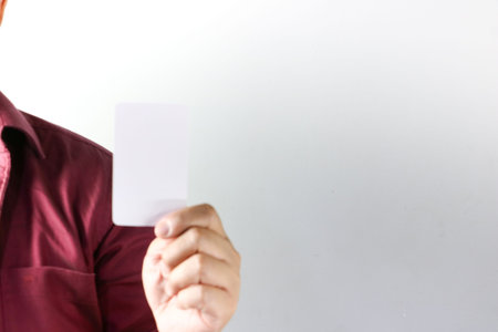Close-up shot of a man left hand gently gripping an empty, plain rectangular paper card, perfect for...