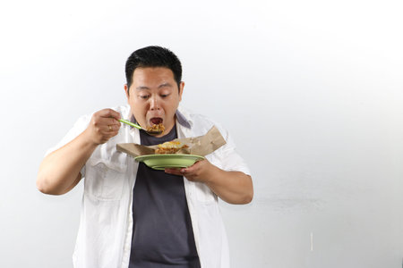 Indonesian man holds a plate of nasi goreng with an open mouth ready to eat