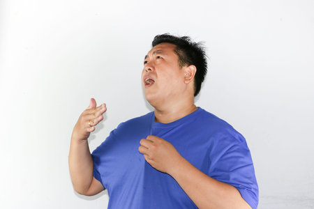 Indonesian guy feeling uncomfortable and sweaty due to high humidity and soaring temperatureの写真素材