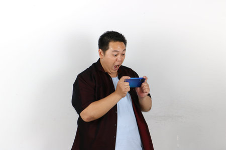 Happy indonesian man demonstrating a smartphone gadget with a pointing gestureの写真素材