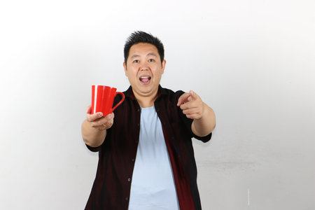 Happy young man with wide smile holding a red tea cup, isolated white backgroundの写真素材