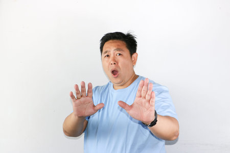 Portrait of asian guy with hands held open in front as a symbol of a firm but polite rejectionの写真素材