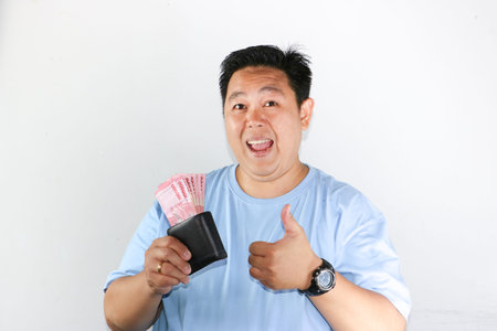 photo of asian man looks delighted while showcasing his wallet for finances freedom and cash savings...
