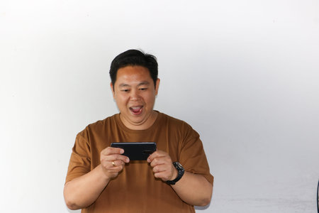 Smiling Asian man holding a smartphone with a blank screen towards the camera for app mockupsの写真素材