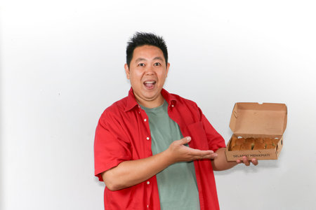 Excited asian man holding an open box of traditional indonesian sweet martabak pancakeの写真素材