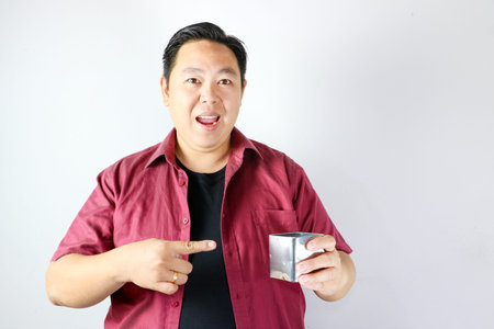 Adult Asian man smiling and presenting a small stainless steel gift box on isolated white backgroundの写真素材