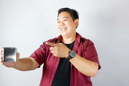 Adult Asian man smiling and presenting a small stainless steel gift box on isolated white backgroundの写真素材