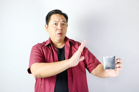Surprised Asian man making a stop gesture to refuse a small stainless steel boxの写真素材