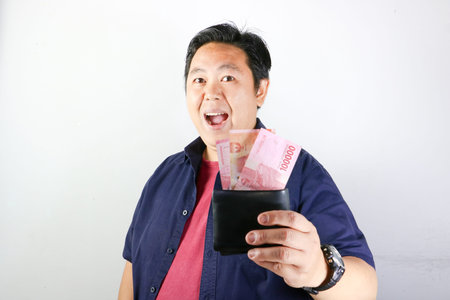 Smiling Asian man in blue shirt points finger at black smartphone screen
