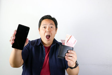 Portrait of Happy Asian man holding black wallet full of Indonesian Rupiah cash