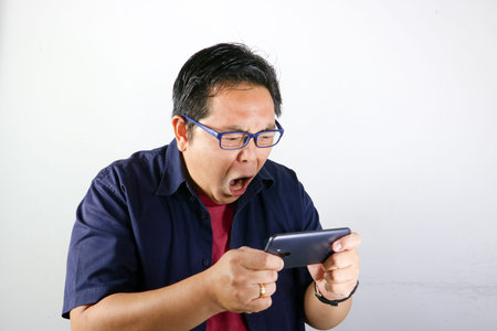 Portrait of Shocked Asian man in glasses holding a smartphone with a wide open mouth