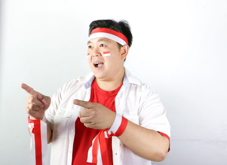Portrait of an excited Asian man with Indonesian flag stickers and a red and white headbandの写真素材