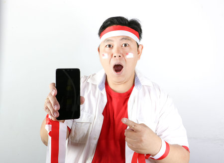 Cheerful Indonesian man celebrates independence day while wearing a patriotic red and white headbandの写真素材