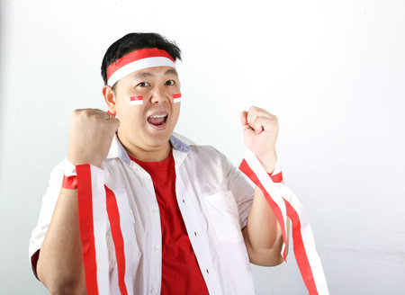 Portrait of a happy Indonesian man showing red and white ribbon for Independence Day, isolated on white background.の写真素材