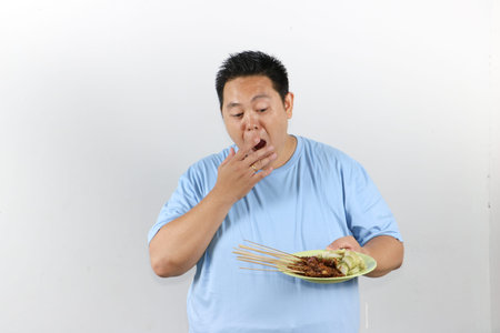 Indonesian man excitedly presenting authentic Indonesian cuisine Tasty chicken satay skewersの写真素材