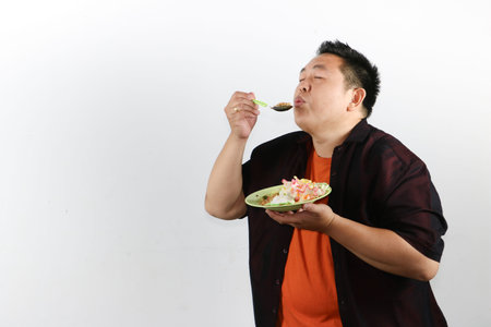 Happy Asian man eating authentic Indonesian fried rice, authentic Southeast Asian food and travel themeの写真素材