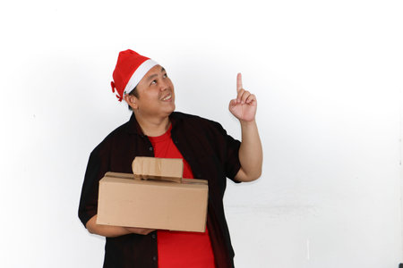 Cheerful Asian man in Santa hat holding mobile phone and showing excitement isolated on white...