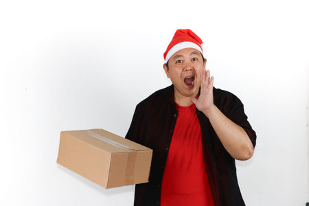 Portrait of happy Asian man in Santa hat holding cellphone for New Year sale promotion on white...