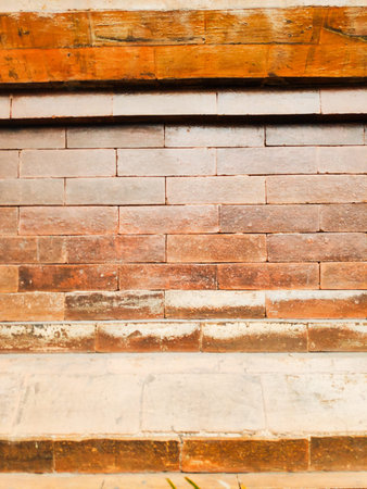 Detailed view of weathered clay bricks arranged in a symmetrical running bond pattern