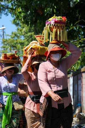 Balinese woman carries sacred offerings on her head in a street parade Denpasar Bali 1 June 2025
