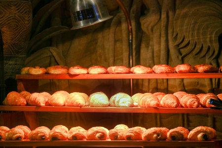 Rows of fresh golden croissants and pain au chocolat on wooden shelves at a luxury hotel breakfast...