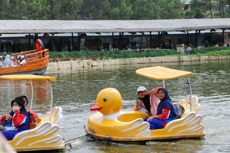 Happy Indonesian families enjoy riding yellow duck shaped paddle boats on a scenic lake in Lembang, Bandung 22 December 2025のeditorial素材