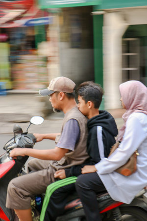 Dangerous riding behavior with a motorcyclist not wearing a safety helmet in a city alley in...