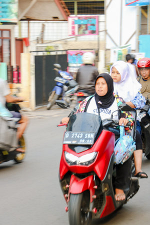 Dangerous riding behavior with a motorcyclist not wearing a safety helmet in a city alley in...