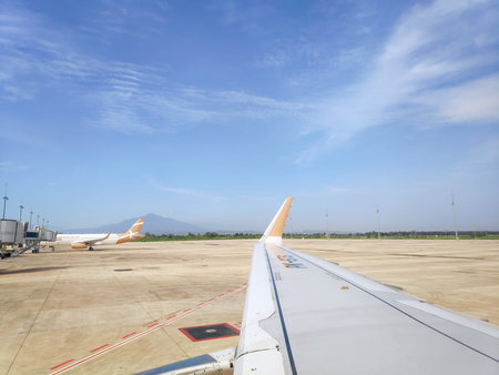 View from an airplane window showing the wing and engine while parked at Kertajati International...