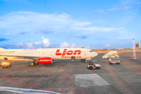 Commercial Boeing 737 900ER aircraft with Lion Parcel livery parked on the sunny apron of Bali...