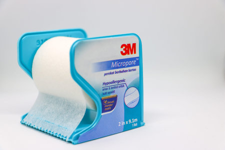 Close up of 3M Micropore surgical paper tape roll in a blue plastic dispenser isolated on white background. Bandung 11 June 2025のeditorial素材