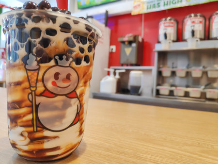 Close up of a mixue boba sundae ice cream in a plastic cup with snowman logo on a wooden table, Bandung 20 May 2025のeditorial素材