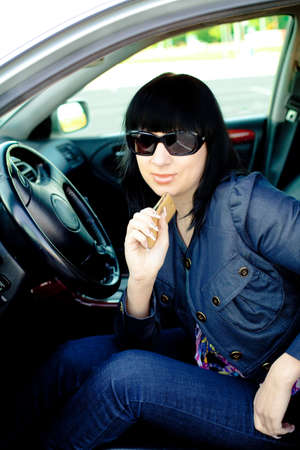 Beautiful young businesswoman with cellphone in her car after workの写真素材